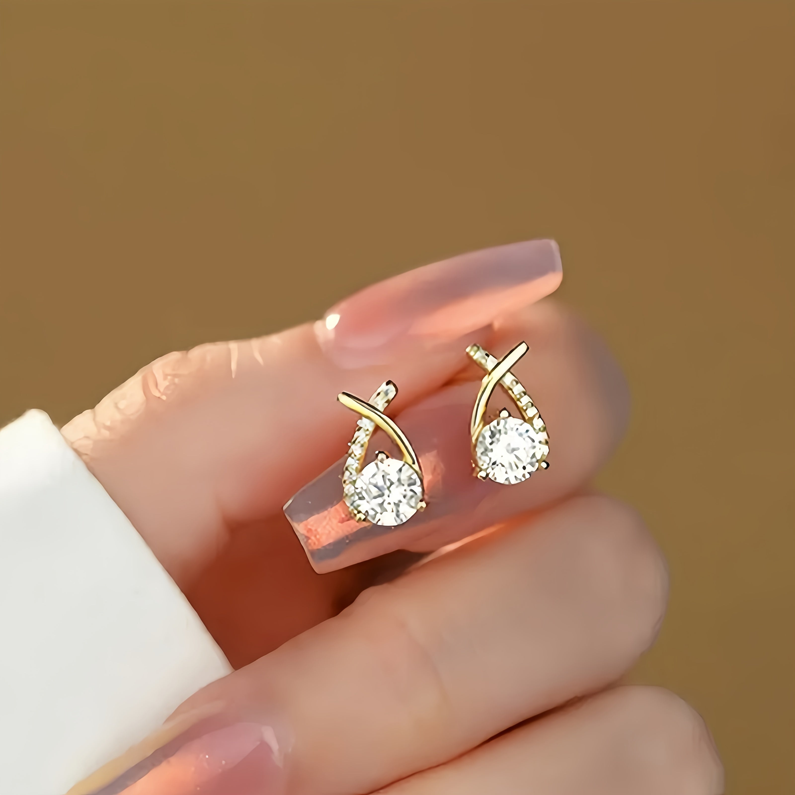 Pendientes tipo stud de cruz dorada con zirconia.